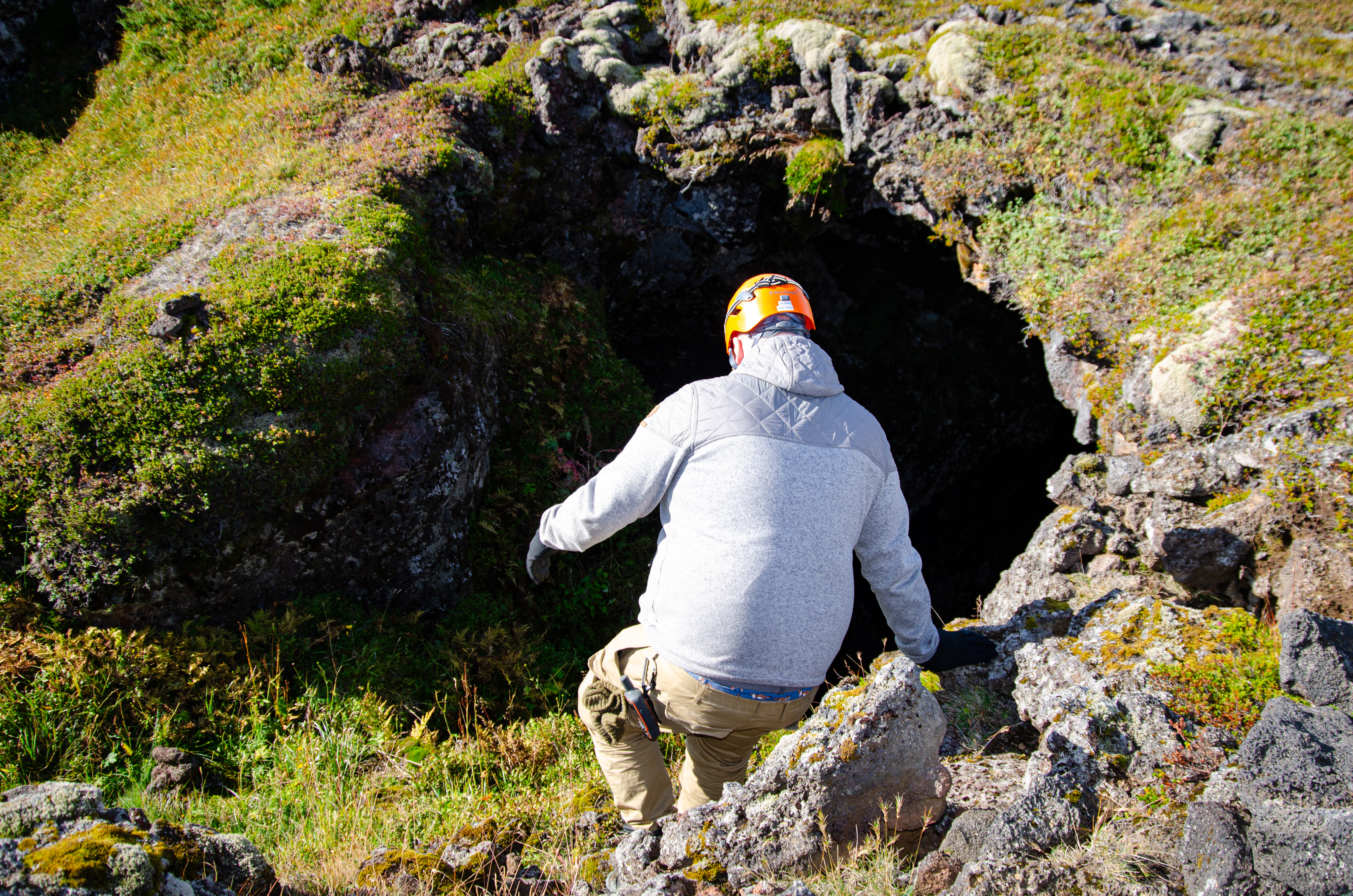 Researcher descending into cave opening