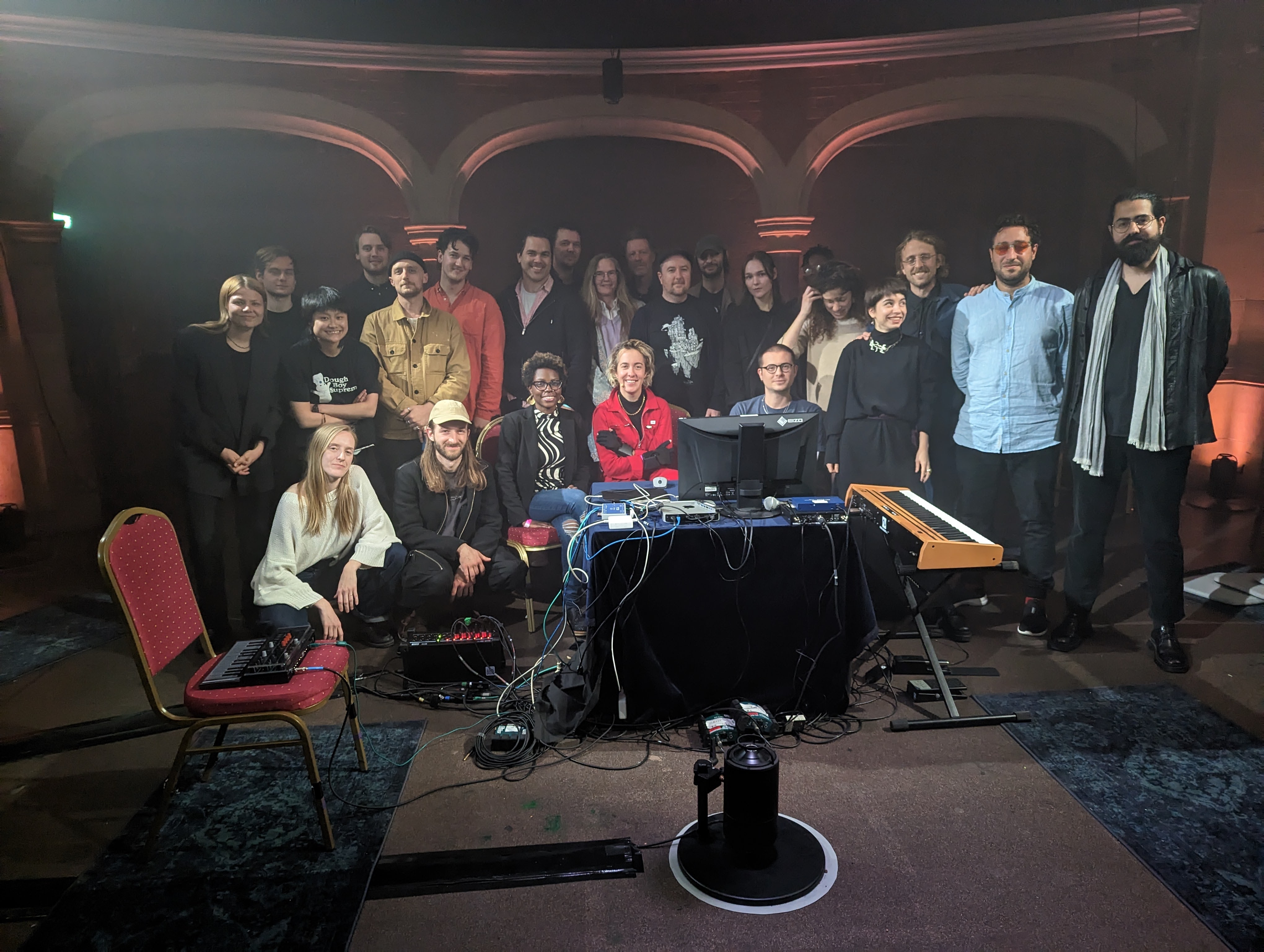 Closing concert — performers at central table, audience surrounding them in Stone Nest
