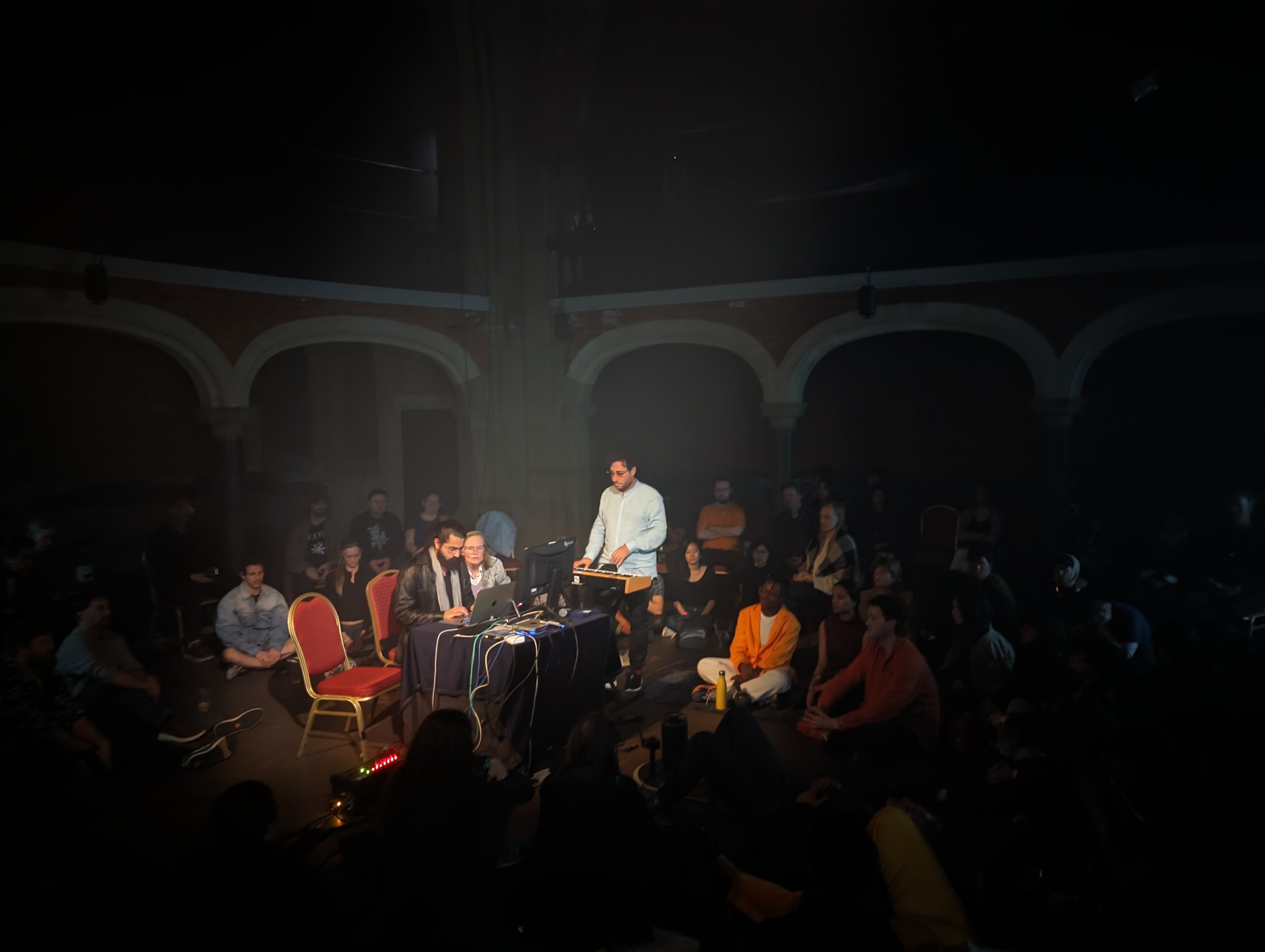 Performers at table in darkness during closing concert